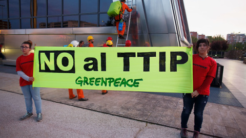 Miembros de Greenpeace muestras una pancarta en protesta contra el TTIP. GREENPEACE.