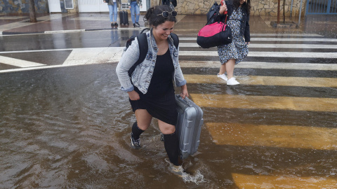 Varias personas cruzan una calle inundada cuando el episodio de lluvias torrenciales ha dejado un registro histórico de 198 litros por metro cuadrado esta madrugada en la ciudad de Castelló.