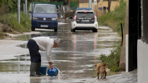 Un hombre retira agua de la calle con dos cubos, este viernes 26 de mayo de 2023, en el camino de la huerta de abajo en Molina de Segura.