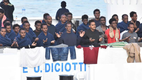 Migrantes rezan a la espera del desembarco del barco italiano de la Guardia Costera italiana en Catania. - EFE