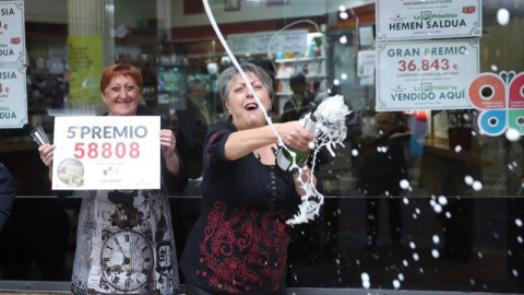 Las loteras María Jesus (d) y Begoña celebran el reparto del quinto premio de la lotería de Navidad, que le ha tocado al número 58808, en un punto de venta de la calle Castaños de la capital vizcaína. | LUIS TEJIDO (EFE)