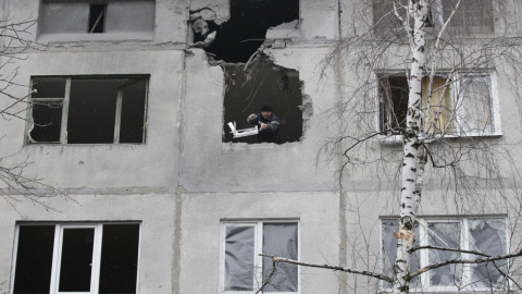 Un hombre lanza escombros desde un edificio en ruinas por los estragos de la guerra en Ucrania./REUTERS