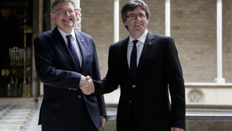 El presidente de la Generalitat, Carles Puigdemont (d), recibe al presidente de la Generalitat Valenciana, Ximo Puig (i) al inicio de la reunión que ambos mandatarios mantuvieron en el Palau de la Generalitat.