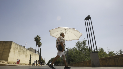 Un hombre se protege del sol con una sombrilla en una jornada de intenso calor.