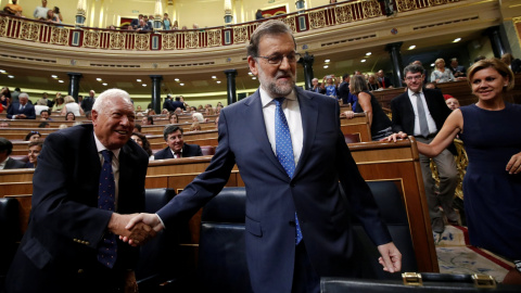 El presidente el Gobierno en funciones, Mariano Rajoy, se da un apretón de manos con Garcia-Margallo antes del debate de investidura en el Congreso de los Diputados. REUTERS/Juan Medina