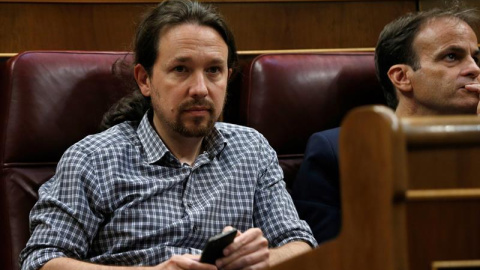 El líder de Unidas Podemos, Pablo Iglesias (izda), en su escaño del hemiciclo del Congreso