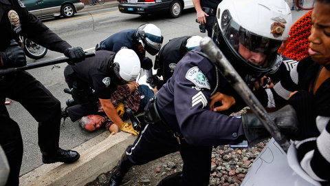 Policías tratan de hacer retroceder a los manifestantes mientras un compañero detiene a un hombre, durante las protestas contra la decisión de la justicia de no acusar a Darren Wilson por la muerte a tiros de Michael Brown. // PATRICK T. FA