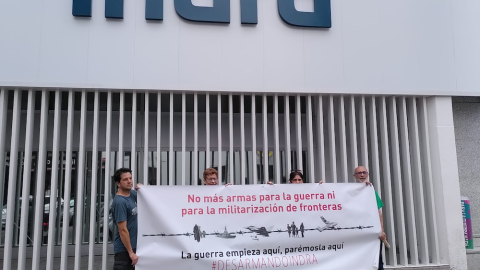 Activistas antimilitaristas despliegan una pancarta delante de la sede de Indra, antes de la Junta de Accionistas de junio de 2022