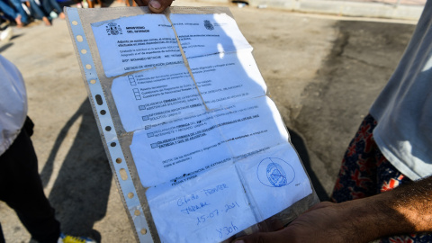 Un joven sostiene un documento de expediente de solicitud de asilo