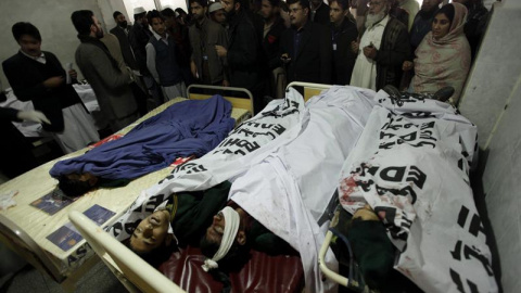 Familiares y miembros de los servicios de emergencia congregados junto a los cadáveres de los alumnos asesinados en el ataque talibán contra una escuela militar. EFE/Arshad Arbab