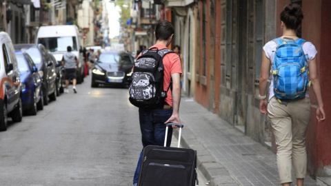 Dos personas con una maleta caminan por la calle. EFE