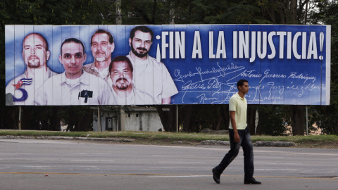 Un hombre camina frente a una valla con la imagen del llamado grupo de "Los Cinco"  en La Hablana. EFE