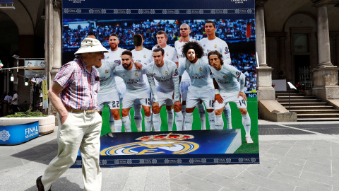 Un hombre pasea por la Piazza dei Duomo, junto a un poster de los jugadores del Real Madrid, para que los aficionados se hagan fotos. REUTERS/Pawel Kopczynski