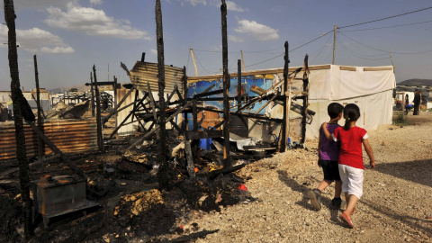 Dos niños pasan junto a los restos de campo de refugiados sirios e Líbano destruido por un incendio. Al menos seis personas murieron. - REUTERS