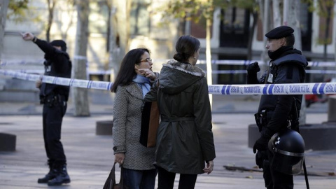 Un agente de Policía Nacional informa a dos ciudadanas en los alrededores de la calle Génova de Madrid. /EFE