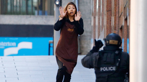 Una rehén corre hacia un oficial de policía, durante el secuestro de una cafetería en el centro de Sidney. /JASON REED (REUTERS)