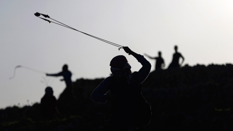 Manifestantes palestinos utilizan hondas para lanzar piedras a los soldados israelíes durante los enfrentamientos cerca de la ciudad cisjordana de Ramala. /MOHAMAD TOROKMAN (REUTERS)