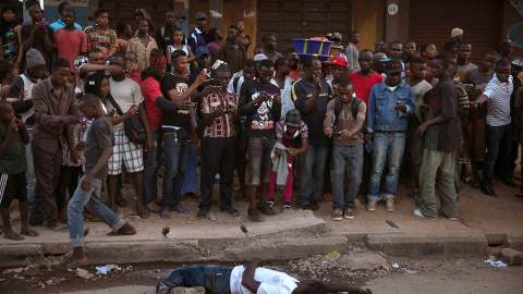 Un grupo de personas observa y fotografía a el cuerpo de una supuesta víctima de ébola en la ciudad de Koidu, en el este de Sierra Leona. /BAZ RATNER (REUTERS)