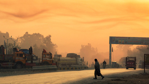 La luz de la salida del sol ilumina el humo en el aire, mientras un hombre cruza la calle cerca de la Base de Operaciones Fenty en la provincia de Nangarhar de Afganistán. /LUCAS JACKSON (REUTERS)