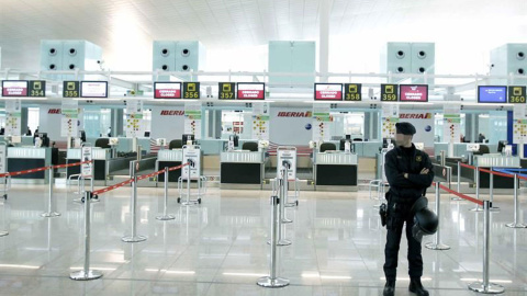 Un mosso de esquadra ante los mostradores de facturación de Iberia, en el aeropuerto de Barcelona-El Prat. EFE/Andreu Dalmau/Archivo