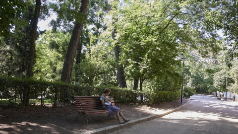 Una señora sentada en un baco del parque Quinta de los Molinos, a 24 de julio de 2022, en el distrito de San Blas-Canillejas, Madrid (España)