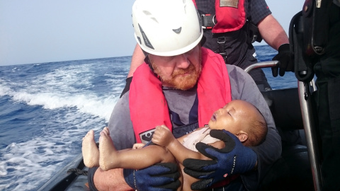 Un cooperante alemán de la organización humanitaria Sea-Watch sostiene el cuerpo de un bebé recogido del mar después de que el barco de refugiados en el que el viajaba naufragase en el Mediterráneo. REUTERS