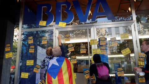 Manifestantes colocando pegatinas en una sucursal del BBVA. - EFE