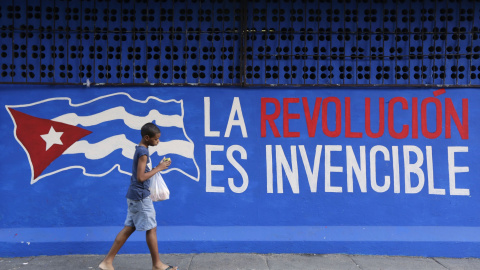 Un niño pasa junto a una pared en La Habana donde se puede leer: "La Revolución es invencible". - REUTERS