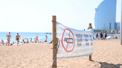 Pancarta que recorda la prohibició de fumar amb l'Hotel W Barcelona de fons.