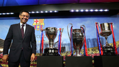 El presidente del FC Barcelona, Josep María Bartomeu, posa con los trofeos de la Liga, Liga de Campeones y Copa del Rey al finalizar su comparecencia. /EFE