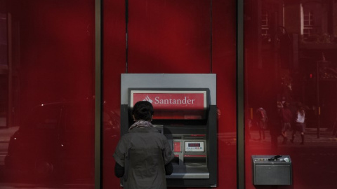 Una mujer utiliza un cajero automático en una oficina del Banco Santander en el centro de Londres. AFP/Carl Court