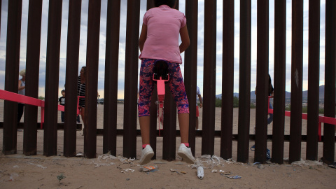 Una menor, vestida de rosa, se eleva en el aire mientras otro joven empuja el balancín desde el otro lado de la frontera. LUIS TORRES (AFP).