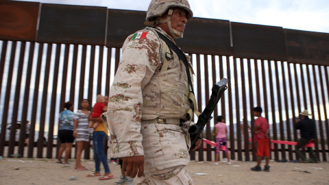 Varios militares del ejército mexicano patrullan la frontera mientras los niños se divierten con el balancín. LUIS TORRES (AFP)