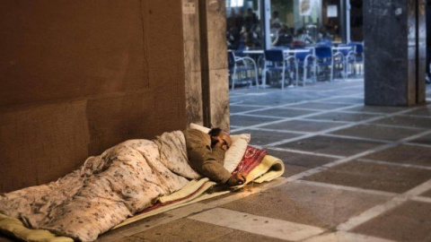 Un hombre sin techo duerme en la acera. EFE