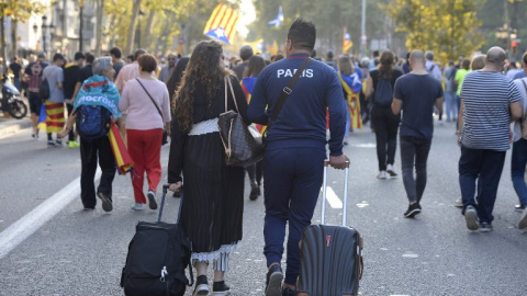 Dos turistas con sus maletas por una calle de Barcelona en la que marcha una manifestación independentista. AFP/Josep Lago