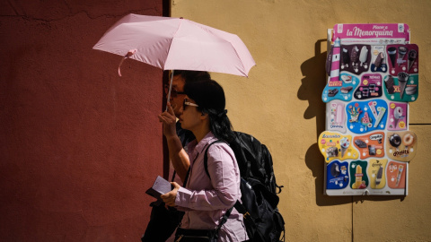 Varias personas pasean por la judería de Córdoba, protegidas por un paraguas del sol, a 29/09/2023.