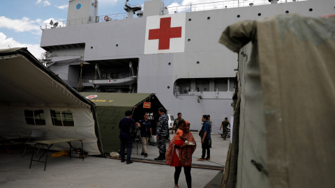 Una mujer sostiene a su hijo mientras espera tratamiento en el barco del hospital de la Armada de Indonesia. REUTERS