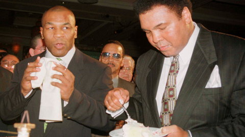 Mohamed Ali/Cassius Clay toma un trozo de su pastel de cumpleaños junto al boxeador Mike Tyson en el MGM Grand hotel de  Las Vegas, el 17 de enero de 1999. REUTERS/Teddy Blackburn