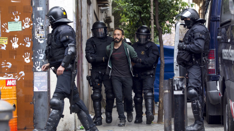 Los Mossos d'Esquadra custodian a uno de los okupas detenidos que han vuelto a entrar en el llamado 'Banc Expropiat' del barrio barcelonés de Gràcia. EFE/Quique García