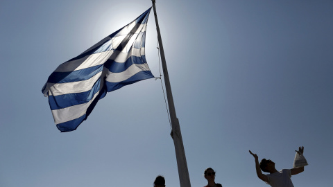 Un grupo de turistas junto a la bandera griega, en la Acrópolis de Atenas. REUTERS/Kostas Tsironis