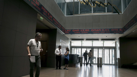 Un hombre camina por la Bolsa de Atenas, cuyos paneles muestran los indicadores del mercado en rojo. REUTERS/Alkis Konstantinidis