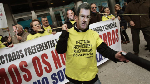 Dos afectados por las preferentes, con máscaras de Feijóo y Rajoy, durante una protesta. / EFE