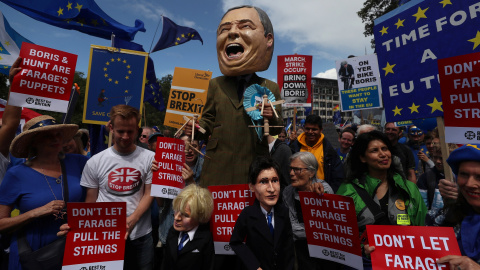 Una persona vestida como el líder del Partido Brexit, Nigel Farage, sostiene títeres que representan a Boris Johnson y Jeremy Hunt durante una marcha anti-Brexit en Londres | Reuters