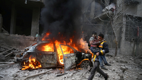 Un miembro de la Defensa Civil de Siria porta a un niño herido en Hamoria, Ghouta Oriental, Damasco. / Reuters