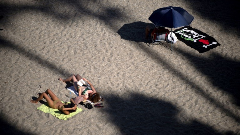 Dos mujeres toman el sol en la playa Burriana, en la localidad mañagueña de Nerja. AFP/Jorge Guerrero