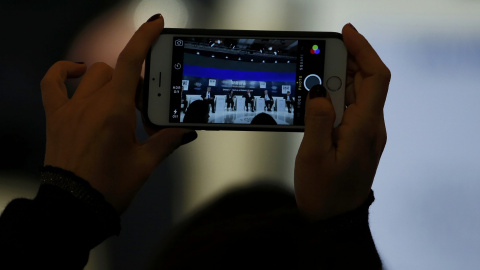 Un asistente a las conferencias del foro de Davos toma una foto con su smartphone. REUTERS/Ruben Sprich