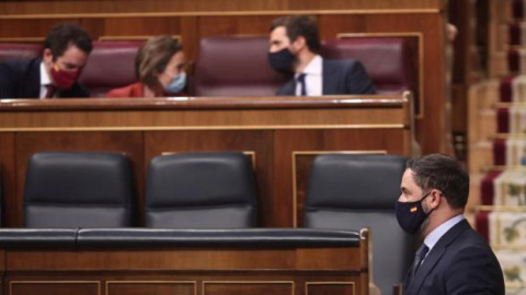 El presidente de Vox, Santiago Abascal, pasa por delante del (I-D) diputado del PP, Teodoro García Egea; la portavoz del PP en el Congreso de los Diputados, Cuca Gamarra; y el presidente del PP, Pablo Casado, durante la segunda sesión del p