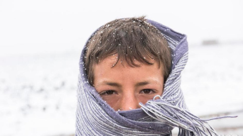 Un joven refugiado sirio se cubre para protegerse del frío en el valle de la Bekaa, en el Líbano, en enero de 2016.-  ACNUR/UNHCR/Haidar Darwish.