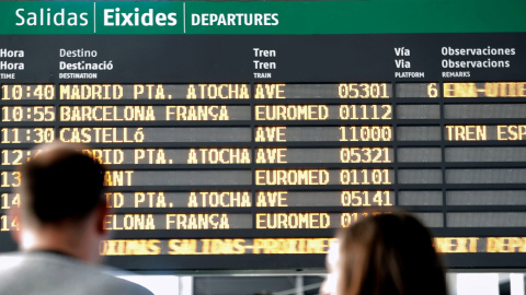 Dos pasajeros observan el horario del AVE a Castellón en el panel de salidas de la estación Joaquín Sorolla de València. EFE/Manuel Bruque