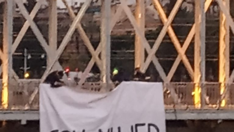 Tres hombres despliegan un cartel en el Puente Nuevo, en Murcia, asegurando: "Soy mujer y no me representan"